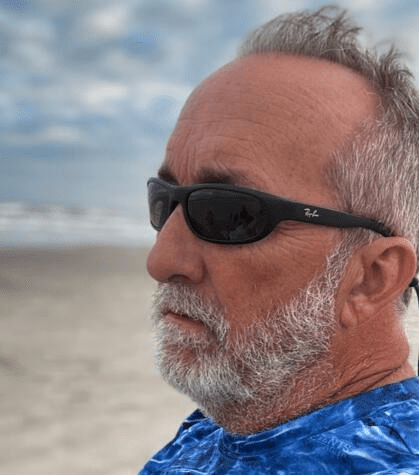 Photo of this website's founder, Jay Thompson, in profile, sitting on a beach